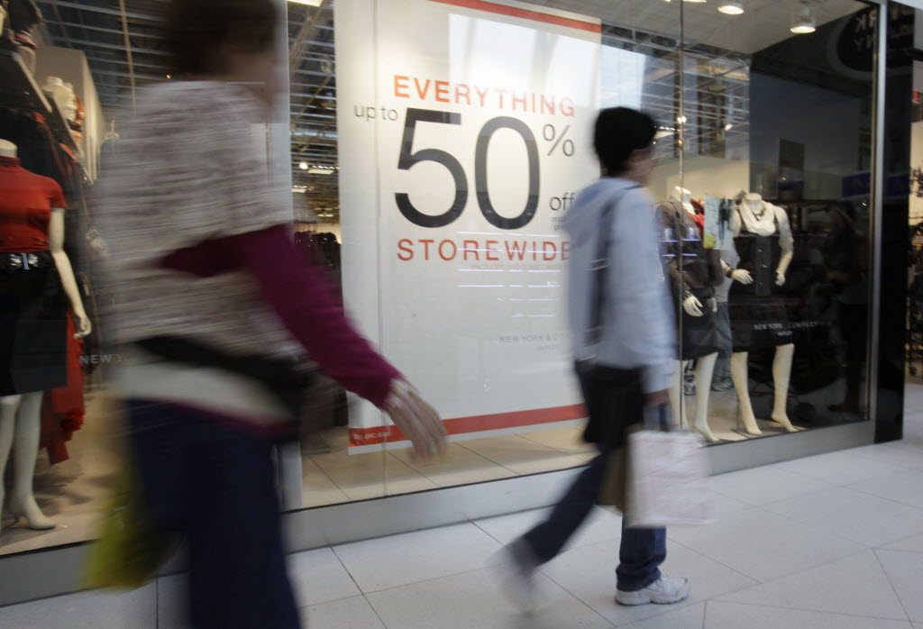 Shoppers walk past a sale sign at the New York &amp; Company outlet store while shopping at Dolphin Mall, in Miami on Nov. 9. As consumers go, so goes the economy.