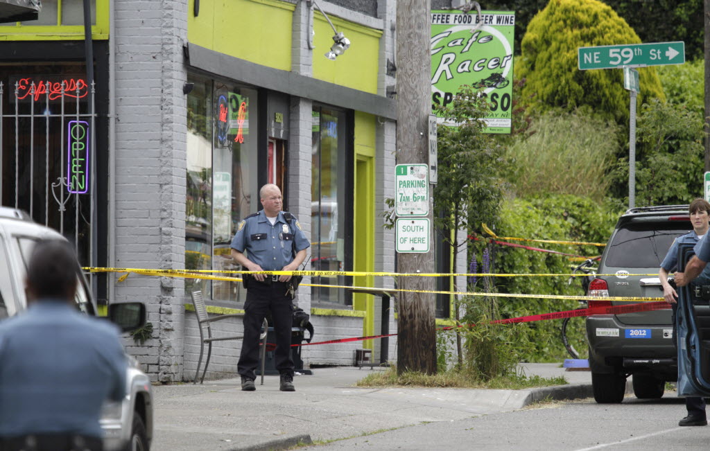 A Seattle Police officer stands outside a cafe where a shooting took place Wednesday. A lone gunman killed four people Wednesday -- three were shot to death at a cafe, and a fourth in a carjacking.
