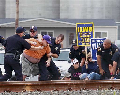 Law enforcement personnel wrestle ILWU Local 21 longshoreman Kelly Muller to the ground as they arrest protesters and try to clear the tracks so a Burlington Northern-Santa Fe grain train can pull in to the EGT grain terminal at the Port of Longview on Wednesday. The union filed a federal lawsuit against local authorities Thursday, accusing them of using brutal tactics while arresting members for non-violent misdemeanors.