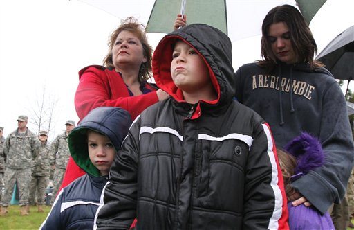 Karen Johnson, upper left, takes shelter under an umbrella with her daughter Sally Glander, right, and Glander's children Kalten Madden, Garion Madden and Adara Madden, foreground from left, during a deployment ceremony for the 3rd Stryker Brigade, 2nd Infantry Division, or &quot;Arrowhead Brigade, at Joint Base Lewis-McChord, near Tacoma, Wash., Tuesday, Nov. 22, 2011. Glander's husband Spc. Chris Glander is part of the unit.