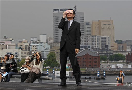 A businessman watches an annular solar eclipse at a waterfront park in Yokohama, near Tokyo, on Monday. Millions of Asians watched as a rare &quot;ring of fire&quot; eclipse crossed their skies early Monday.