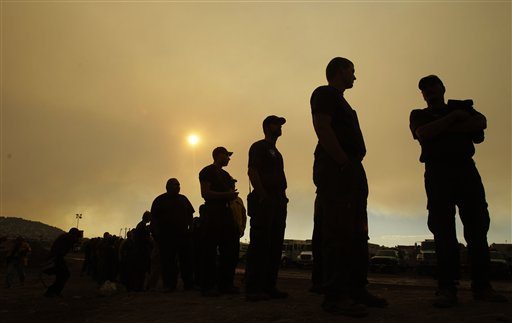 Firefighters line up for a meal as smoke from the Wallow Fire fills the sky at an incident command center in Eagar, Ariz., Thursday, June 9, 2011.