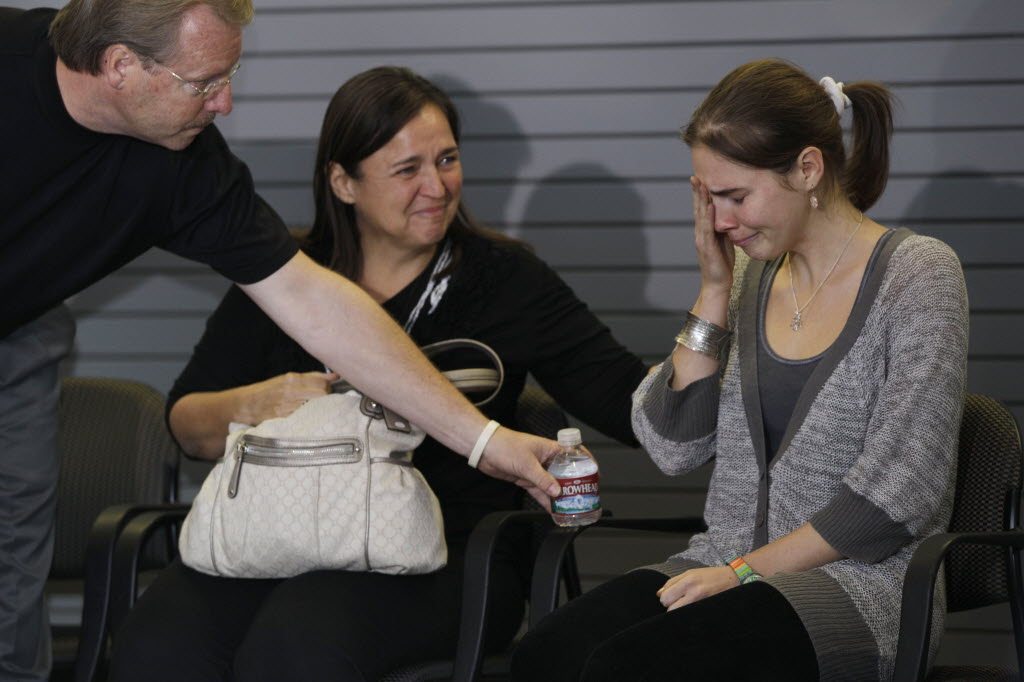 Amanda Knox, right, is offered water by her father Curt Knox as her mother, Edda Mellas looks on as they wait to talk to reporters, Tuesday in Seattle.