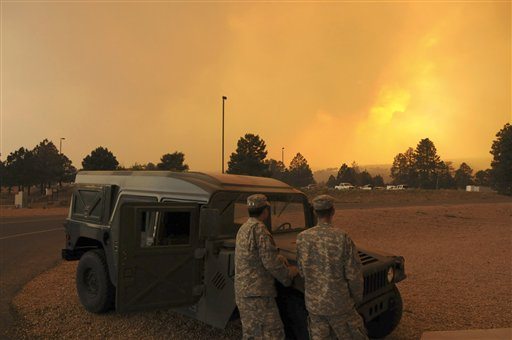 New Mexico Army National Guardsmen Pfc. Sam Fischer , right, and Spc. Orlando Bencomo, left, both of Albuquerque, watch the sky glow orange from smoke and the setting sun, while manning an observation post near the entrance to Los Alamos National Laboratory, in Los Almos, N.M., Monday, June 27, 2011. A fast-moving wildfire has broken out in New Mexico and forced officials at the Los Alamos National Laboratory to close the site Monday as residents nearby evacuate their homes.