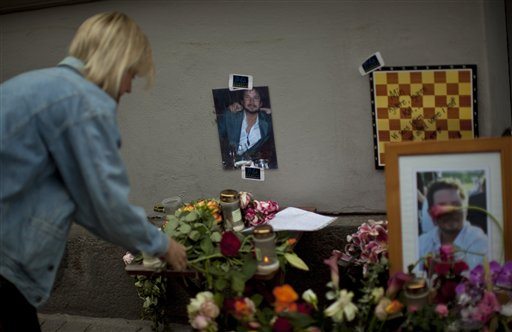 A woman places flowers next to the photo of Kai Hauge, a man killed in last week's bomb blast in Oslo, Norway, Wednesday, July 27, 2011. Norwegian police on Tuesday began releasing the names of those killed in last week's bomb blast and massacre at a youth camp, an announcement likely to bring new collective grief to an already reeling nation.