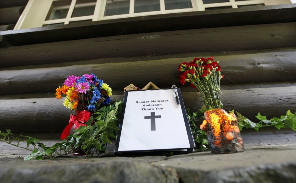 Flowers stand next to a small memorial book for Mount Rainer National Park Ranger Margaret Anderson at the Nisqually entrance to the park Tuesday near Ashford. The park remained closed while the investigation continued a day after searchers found the body of the gunman suspected of shooting and killing Anderson on Sunday.