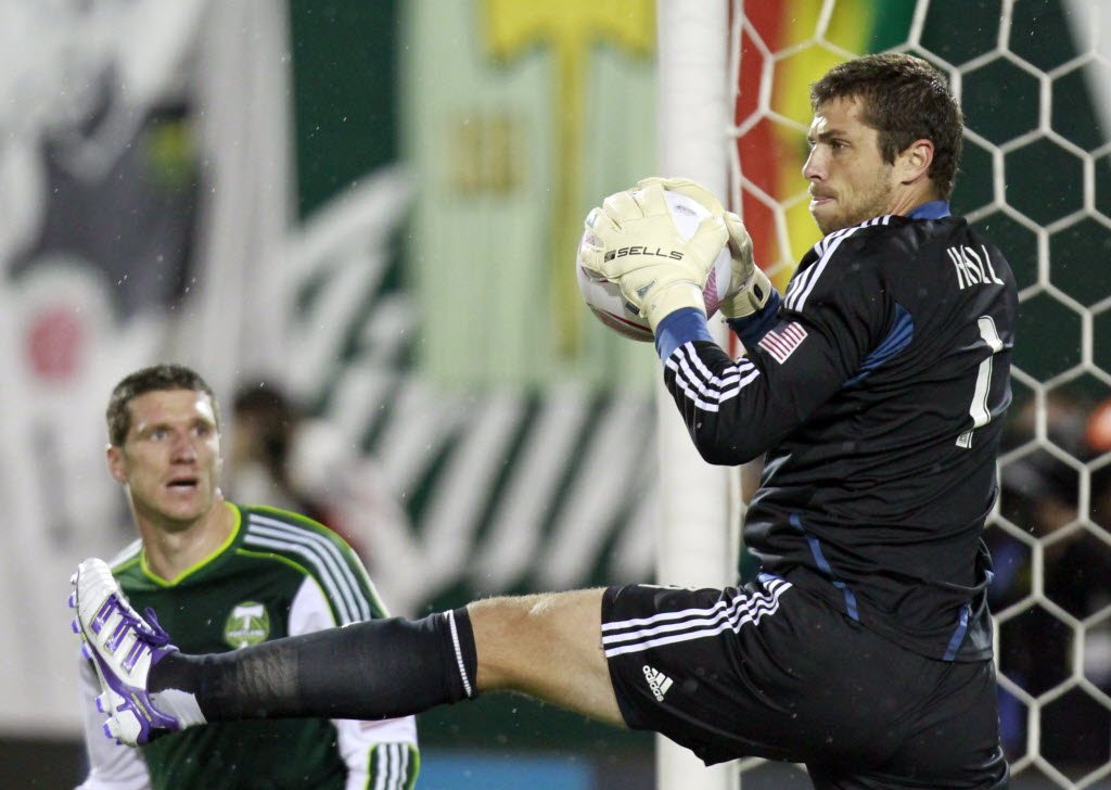 Houston Dynamo goalkeeper Tally Hall, right, pulls in a corner kick as Portland Timbers forward Kenny Cooper watches during the first half of an MLS soccer match in Portland Friday.