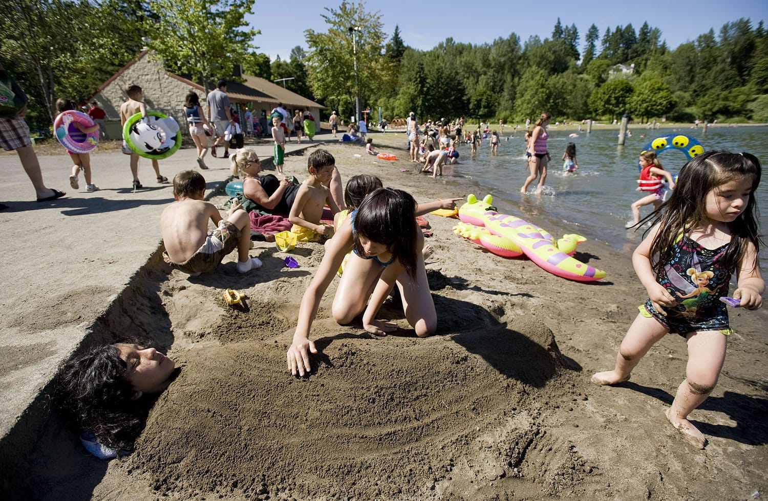 Fatima Barrios, 11, from Vancouver, is buried by her cousins Kimberly Hernandez , 14, and Jolie Maldonado, 3, both visiting from California, at Klineline Pond at Salmon Creek Park, Thursday, June 24, 2010.