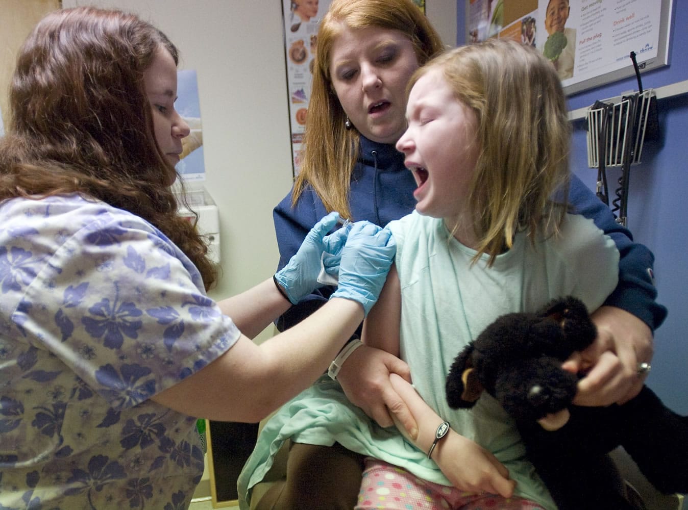 Barbie Allmaras of Heisson holds her daughter Ellen, 7, as medical assistant Jenny Gager injects the girl with a influenza vaccine at Kaiser Permanente's Salmon Creek clinic.