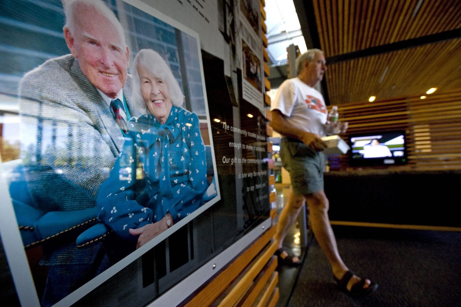 Rolf Adams, of Vancouver, walks past a photograph of Ed and Mary Firstenburg inside the lobby of the Firstenburg Community Center on Aug. 23, 2010.