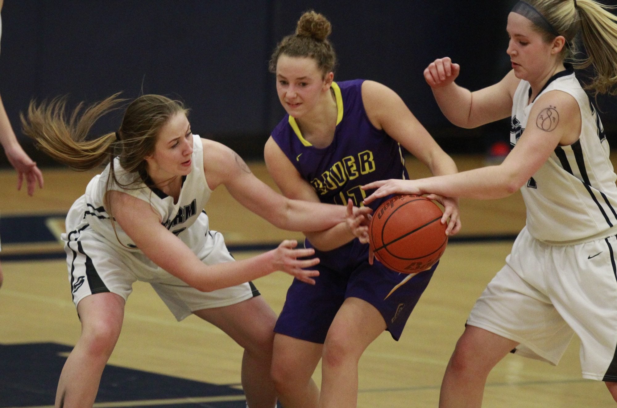 Kate Kraft (center) of Columbia River tries to hold on to the ball as Ashlee Comastro (left) and Kirsten Johnson (right) of Skyview defend.