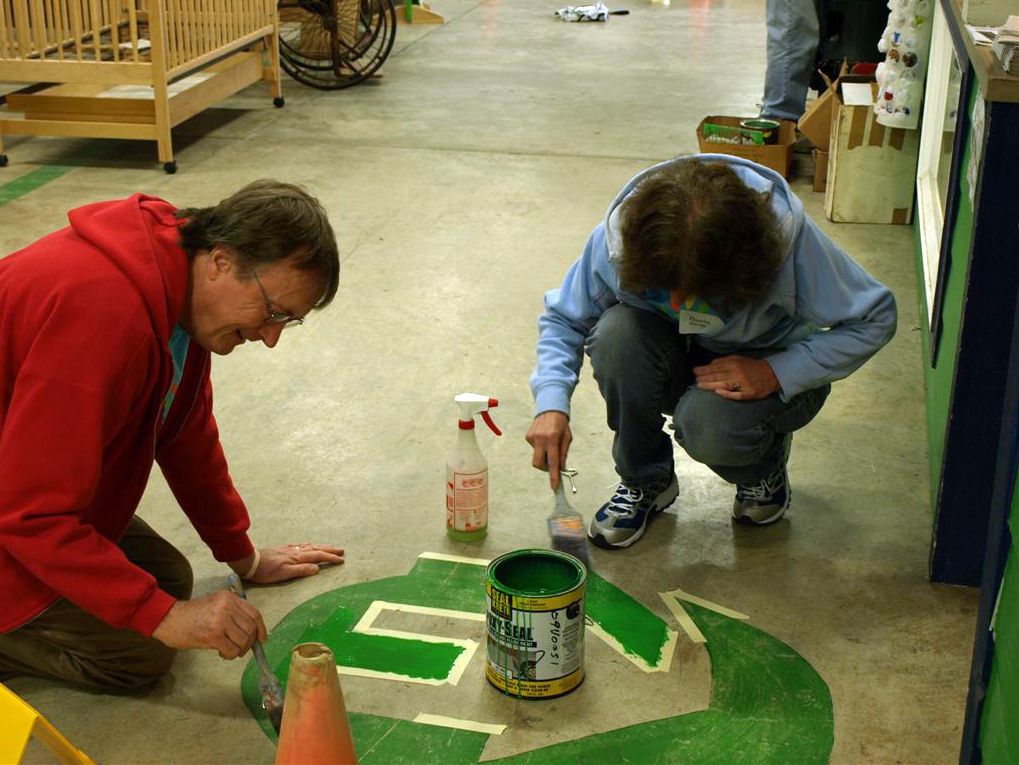 Phillip George, left, a Comcast employee, and Aurelia George paint a logo on the floor of the Habitat ReStore in Vancouver on April 30 as part of Comcast Cares Day.