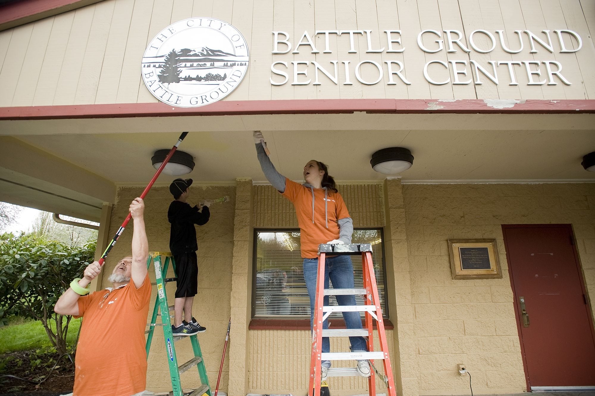 Volunteers Arturo Cortez, from left, Colby Gray, 13, and Kelsey Gray, 15, prime the Battle Ground Senior Center for a paint job.