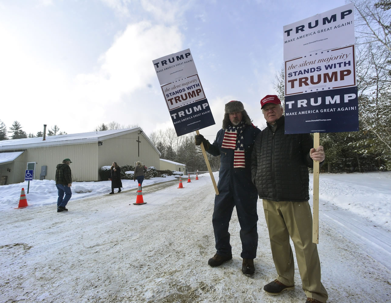 James Wall and H. Gregory Johnson, from Swanzey, N.H., hold signs of support for Republican presidential candidate Donald Trump outside the Swanzey, N.H. polling station during the New Hampshire primary on Tuesday.