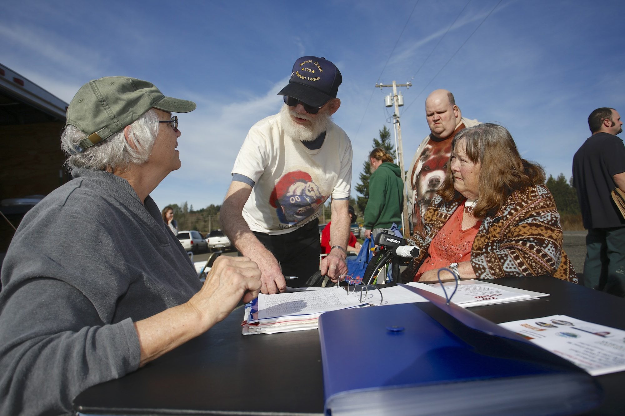 Volunteer Kathryn Thornton, far left, checks in Leonard Barnes, Dale Barnes and Linda Barnes (left to right), of La Center, at the Lewis River Mobile Food Bank distribution site in the unincorporated View area near La Center.