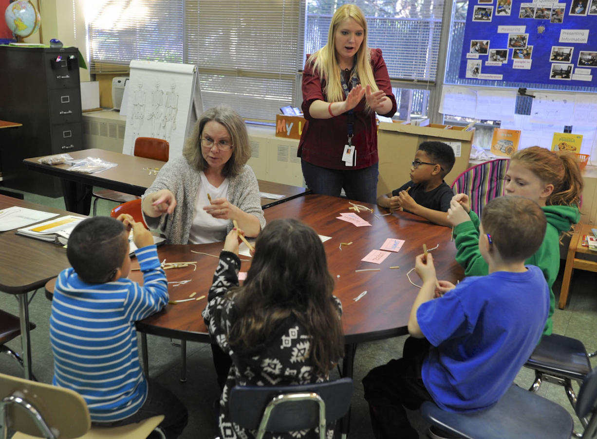 Stephanie Alves deLima, seated, with the assistance of intern Kylee Craven, standing, teaches second-, third- and fourth-grade students about ligaments, tendons and bones at the Washington School for the Deaf on Feb. 8.
