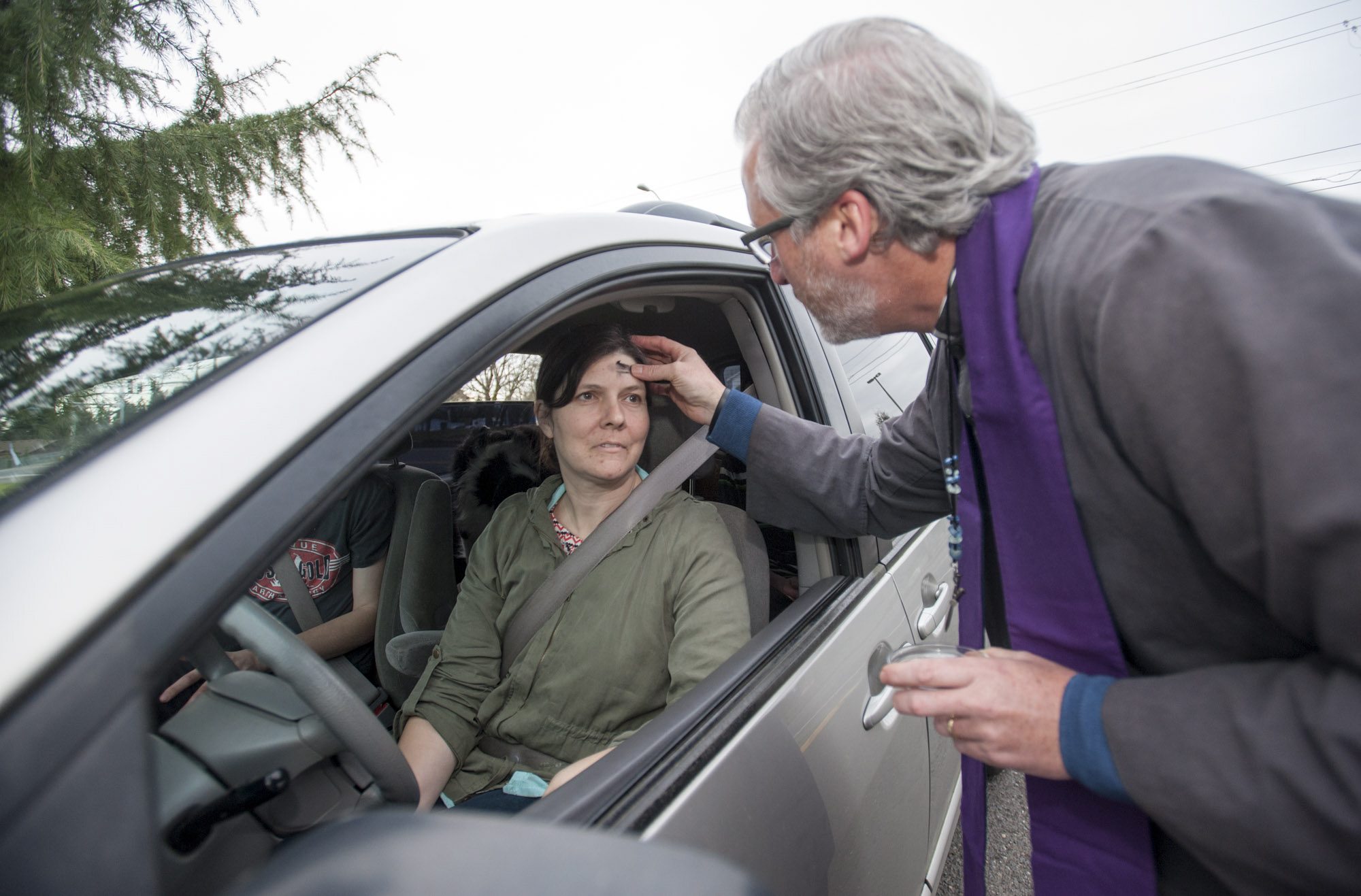The Reverend Tom Warne offers  "Ashes to Go "  to passersby Julie Davis on Ash Wednesday in front of Church of the Good Shepherd in Vancouver Wednesday February 10, 2016.