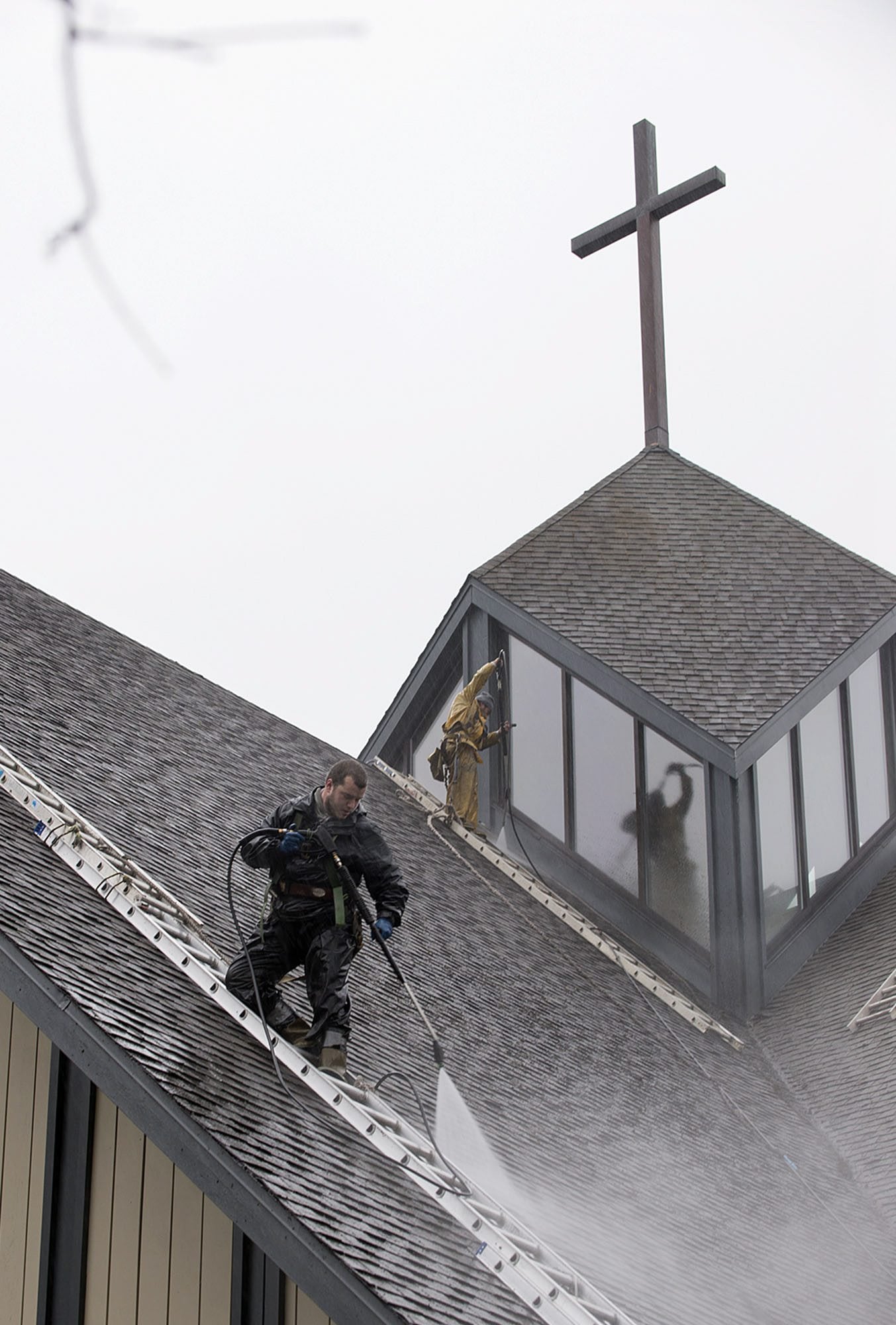 Tyler Tomlin, left, and Joel Perez of Bill&#039;s Pressure Wash, Painting &amp; Roofing clean a roof section at St. Joseph Catholic Church on Friday morning.