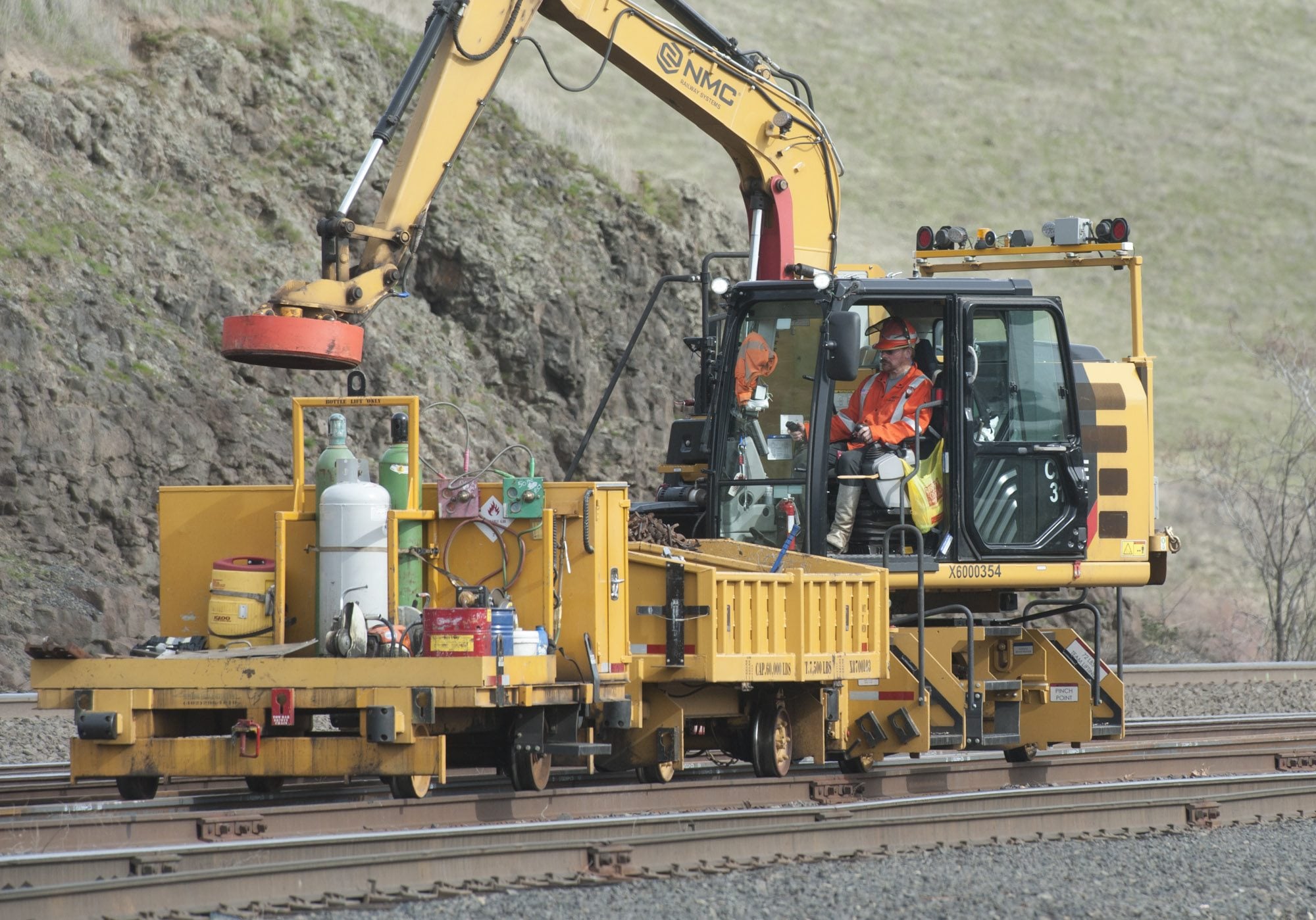 A worker uses an electromagnet to remove metal debris during BNSF rail upgrades in Wishram on Tuesday. The company is investing $220 million in infrastructure upgrades in Washington state.
