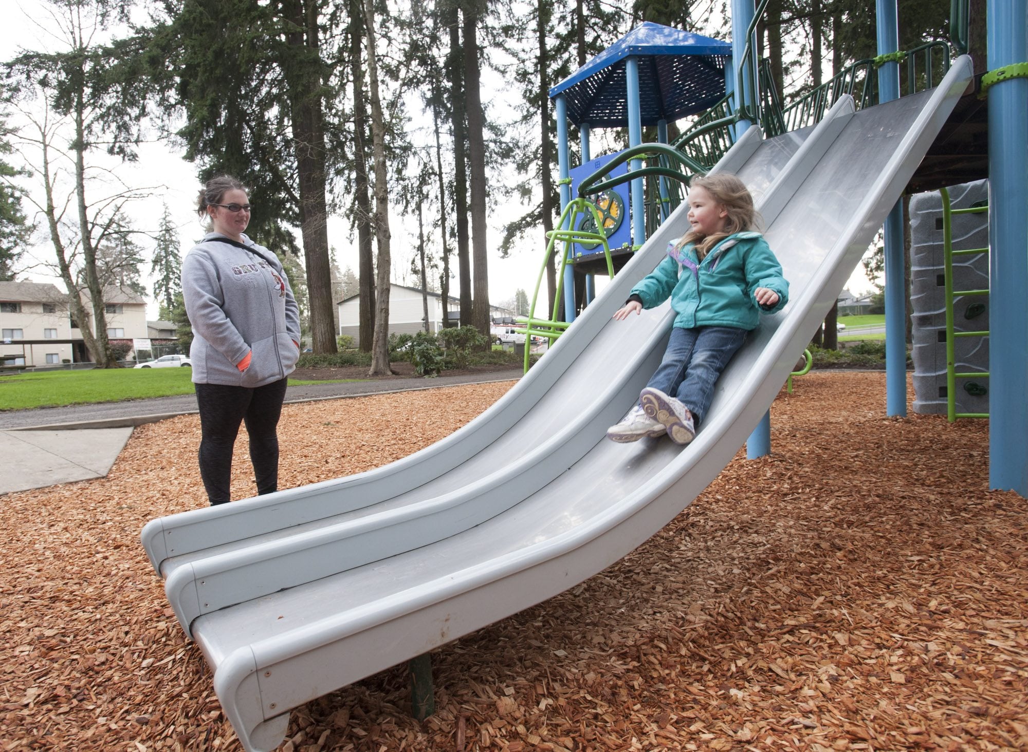 Kystran Knight, 3, slides on a new play structure as her mother, Mariah Watts, watches. Stockford Village Neighborhood Park was updated last month. A bright, new place structure has replaced old monkey bars and a swing set.