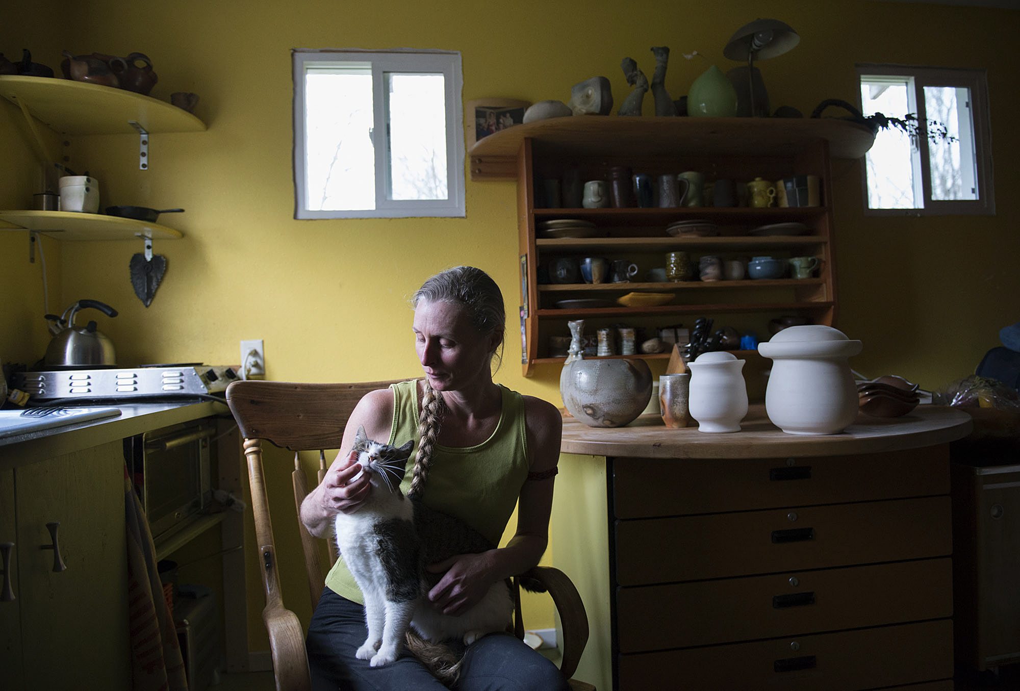 Potter Careen Stoll pets her cat, Butoh, while surrounded by some of her work at her studio in Battle Ground. Taking breaks is important for Stoll to stay healthy as she is basically a one-woman factory.