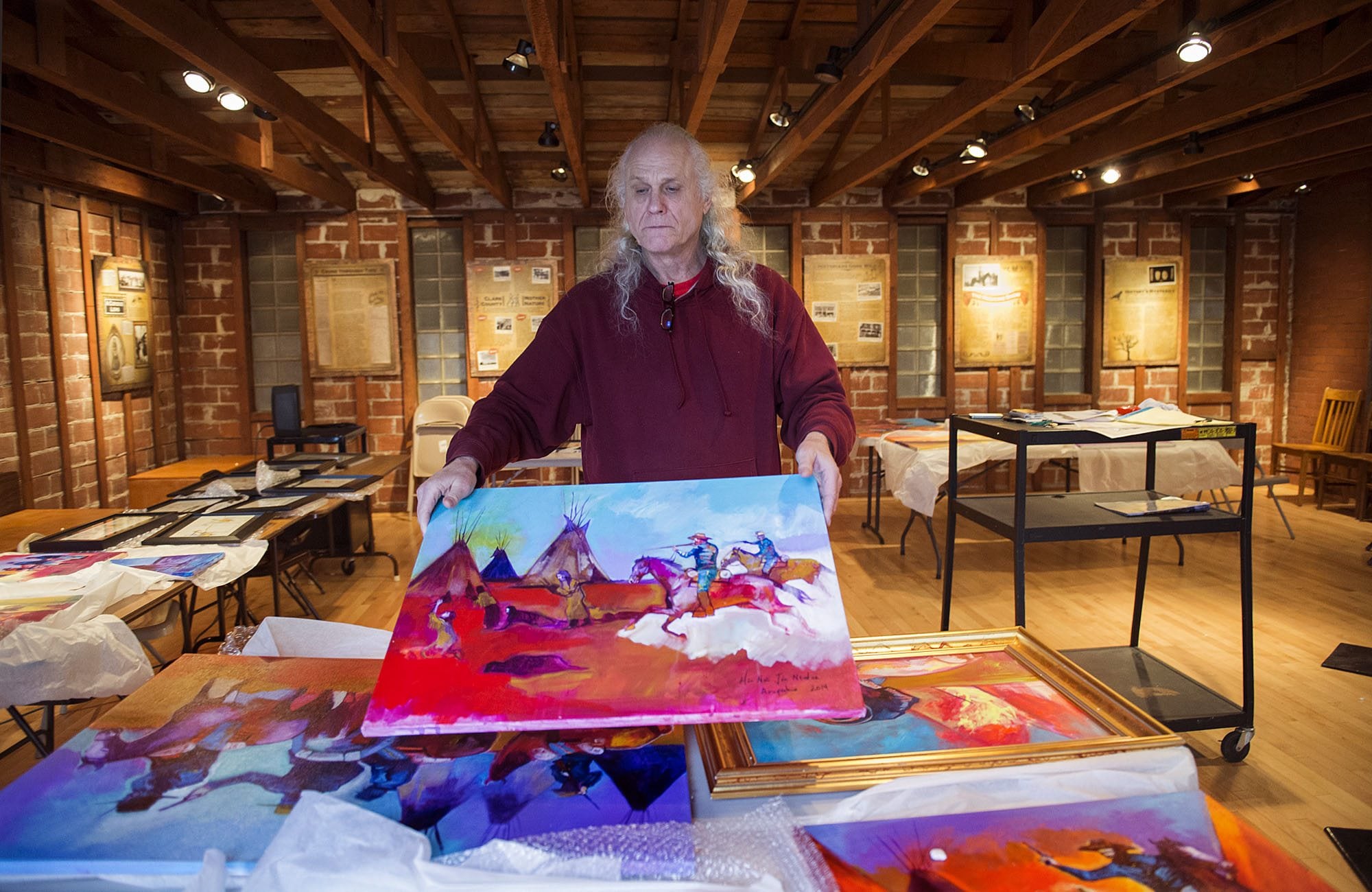 Roben White holds the painting &quot;Cowards&quot; by Brent Learned while unpacking an exhibit documenting the 1864 Sand Creek, Colo., massacre for the &quot;One November Morning&quot; exhibit at the Clark County Historical Museum. White, a museum volunteer, is a descendant of massacre survivors.