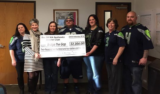 Lynn Miller, Bridge the Gap board chair, second from left, is presented a check from Seahawks Booster Club members, from left, Wendy Rawlings, Miller, Deanna Bevans, Larry Bevans, Julie Gutenberger, Brandi Bazurto and Ryan Gutenberger.