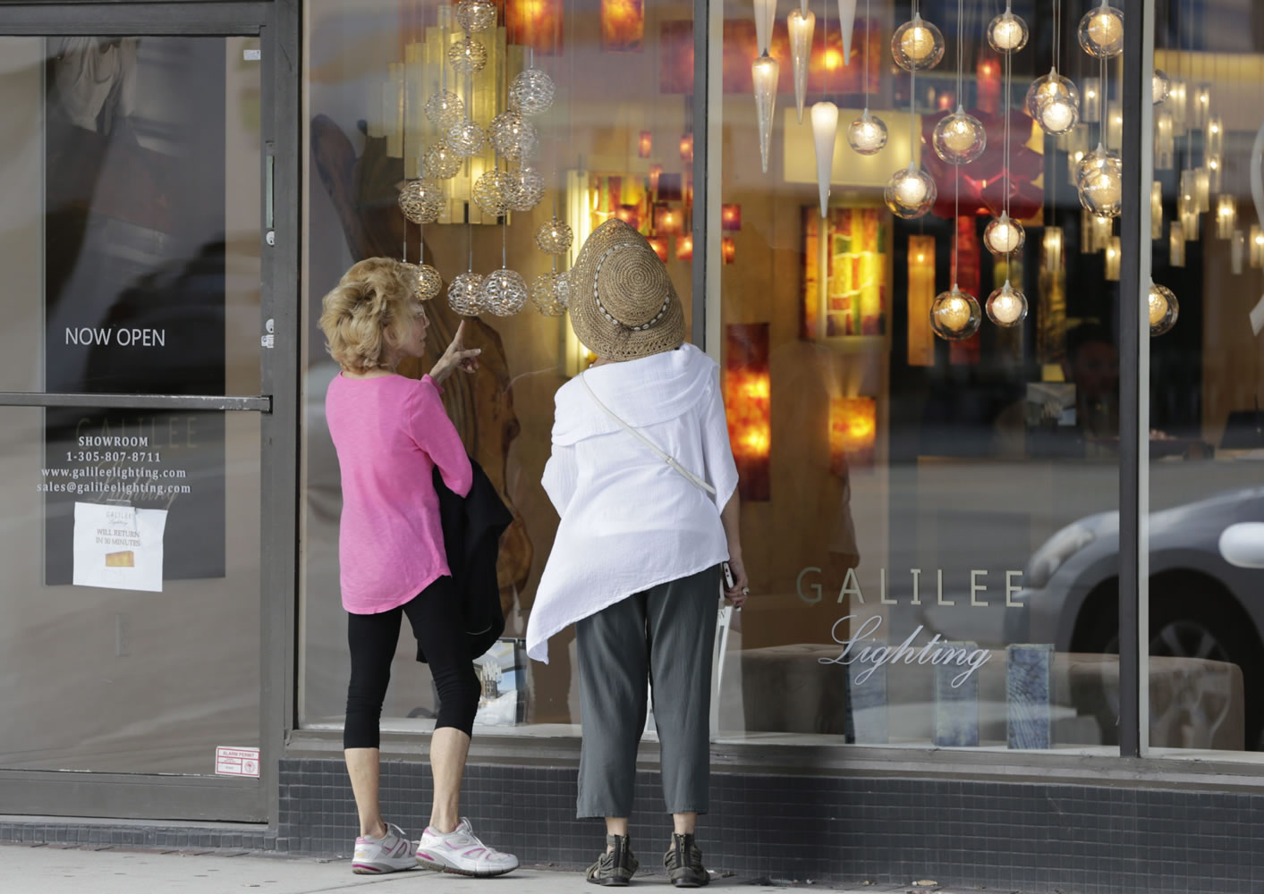 Shoppers stop Feb. 3 to look in the window of a lighting store in the Design District of Miami Beach, Fla. On Friday, the Commerce Department issues the second of three estimates of how the U.S. economy performed in the October-December quarter.