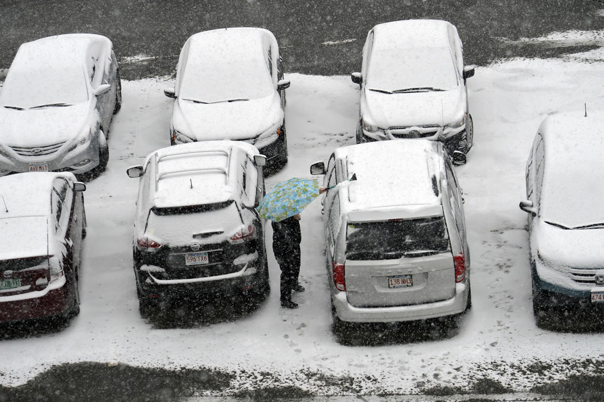 A woman cleans off her snow-covered car after work Monday in Pittsfield, Mass. The second winter storm in four days to hit the Northeast centered on New England on Monday, bringing howling winds and coastal flooding and the threat of more snow.