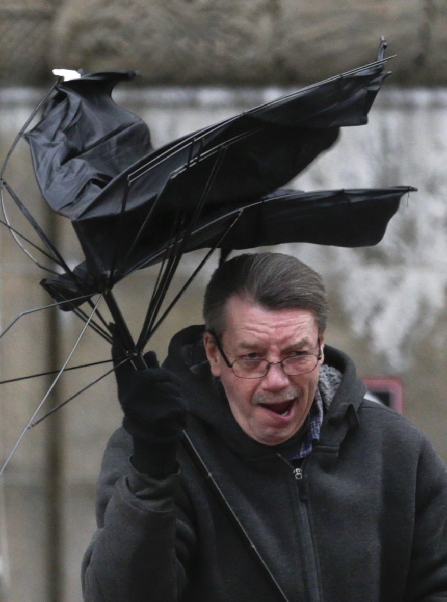 A pedestrian loses his umbrella to high winds and rain Tuesday while walking near the state Capitol in Albany, N.Y.