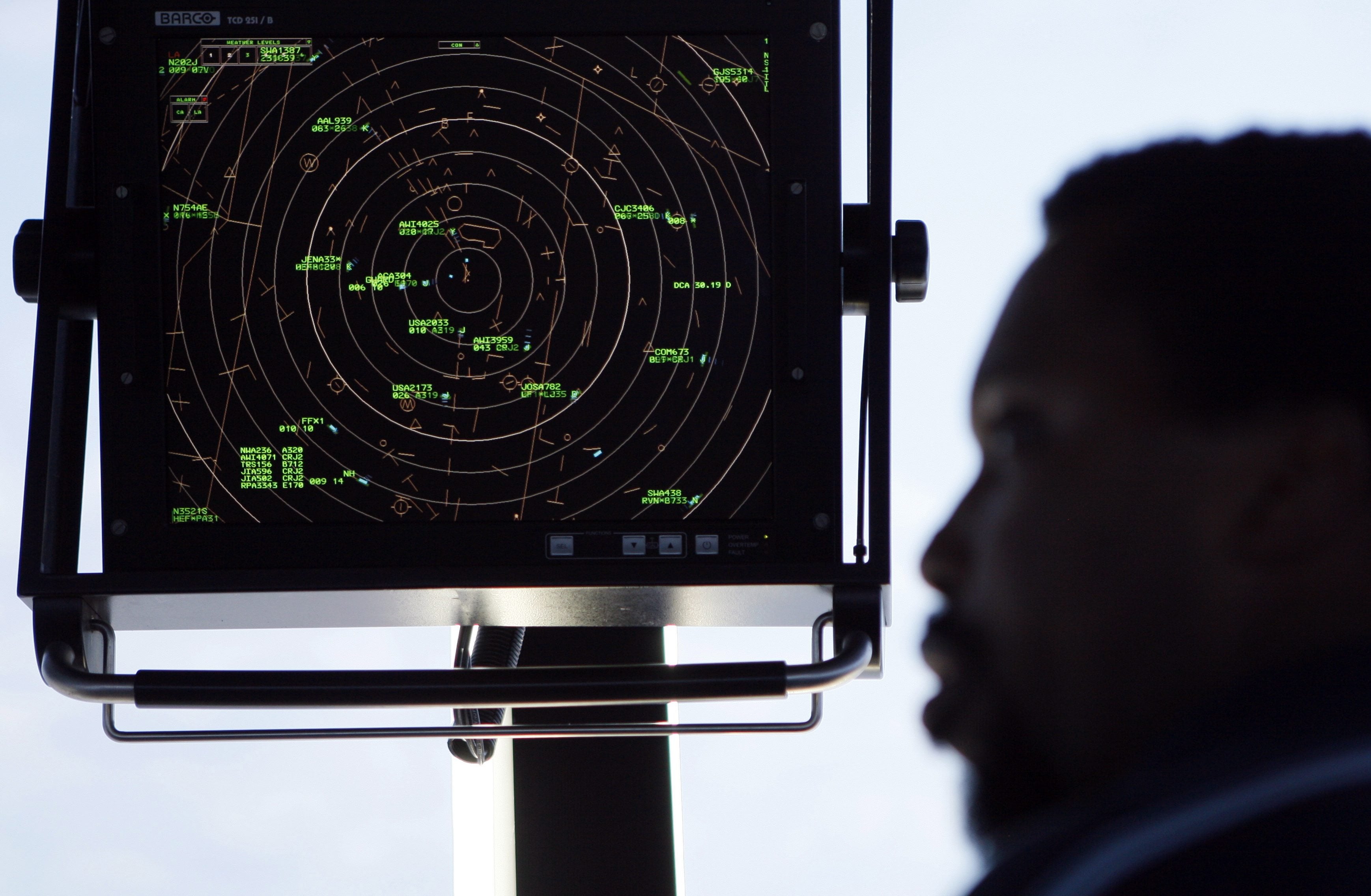 An air traffic controller stands beneath a radar screen in the control tower at Washington&#039;s Reagan National Airport.
