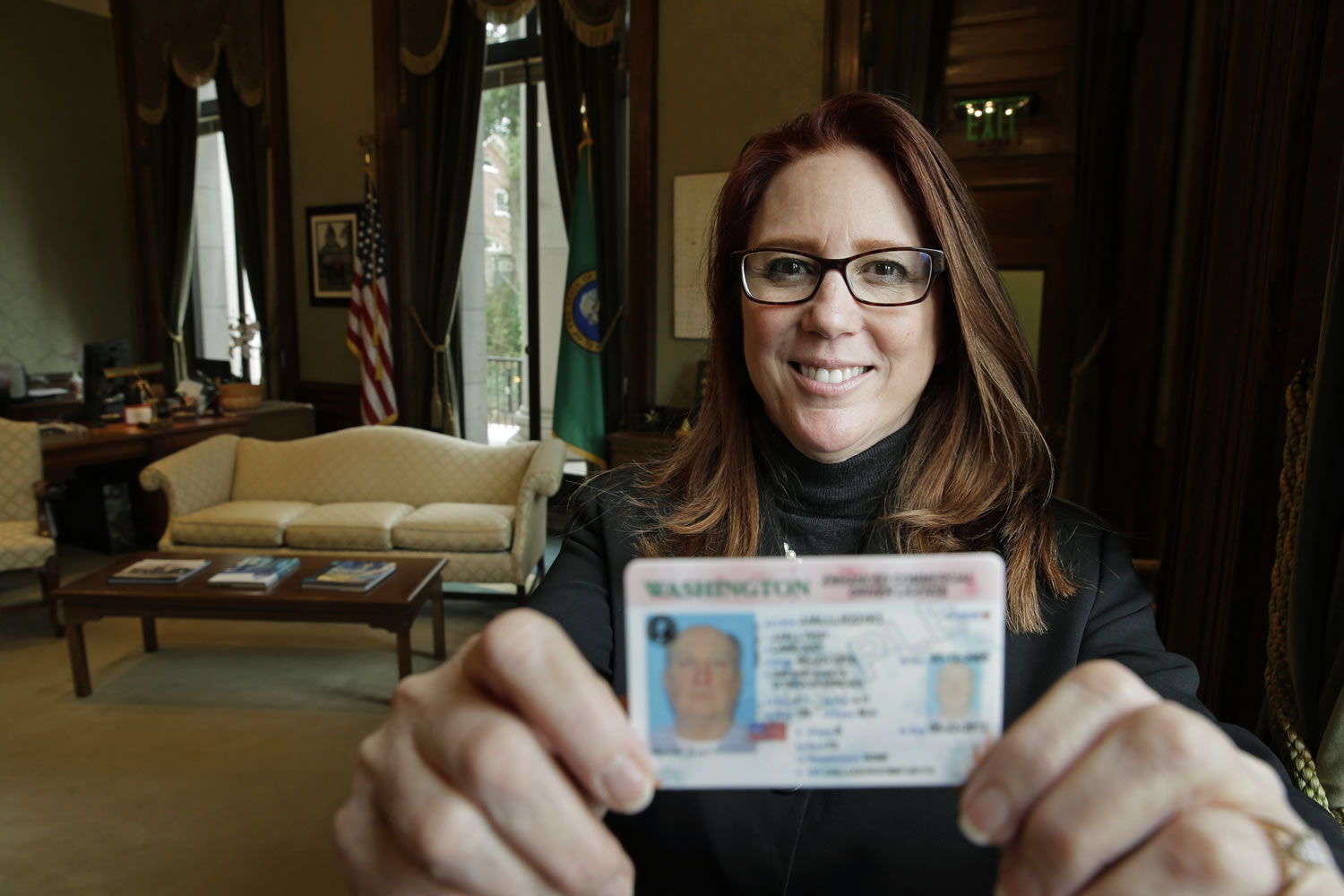 In this photo taken Feb. 1, 2016, Washington Secretary of State Kim Wyman poses for a photo in her office in Olympia, Wash. while holding a sample of a Washington state enhanced drivers license. Months after Washington state saw record low voter turnout, Wyman and several lawmakers say they want to help increase voter engagement with automatic voter registration for some Washingtonians. Senate Bill 6379 and House Bill 2682 would automatically register people who arent on the voter rolls but already have or apply for an enhanced driver's license or commercial drivers licenses. (AP Photo/Ted S.