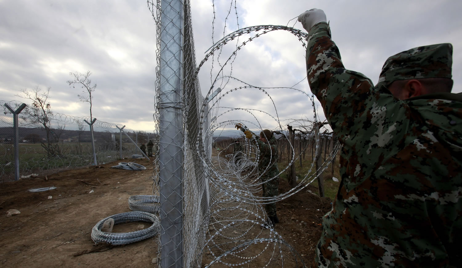 Macedonian Army soldiers attach a razor wire to a fence on Feb. 8 on the border line with Greece, near the southern Macedonian town of Gevgelija, Six nations from Central and Eastern Europe meet Monday in Prague to discuss plans for a new &quot;line of defense&quot; for Europe that involves a double fence along Greece&#039;s northern border.
