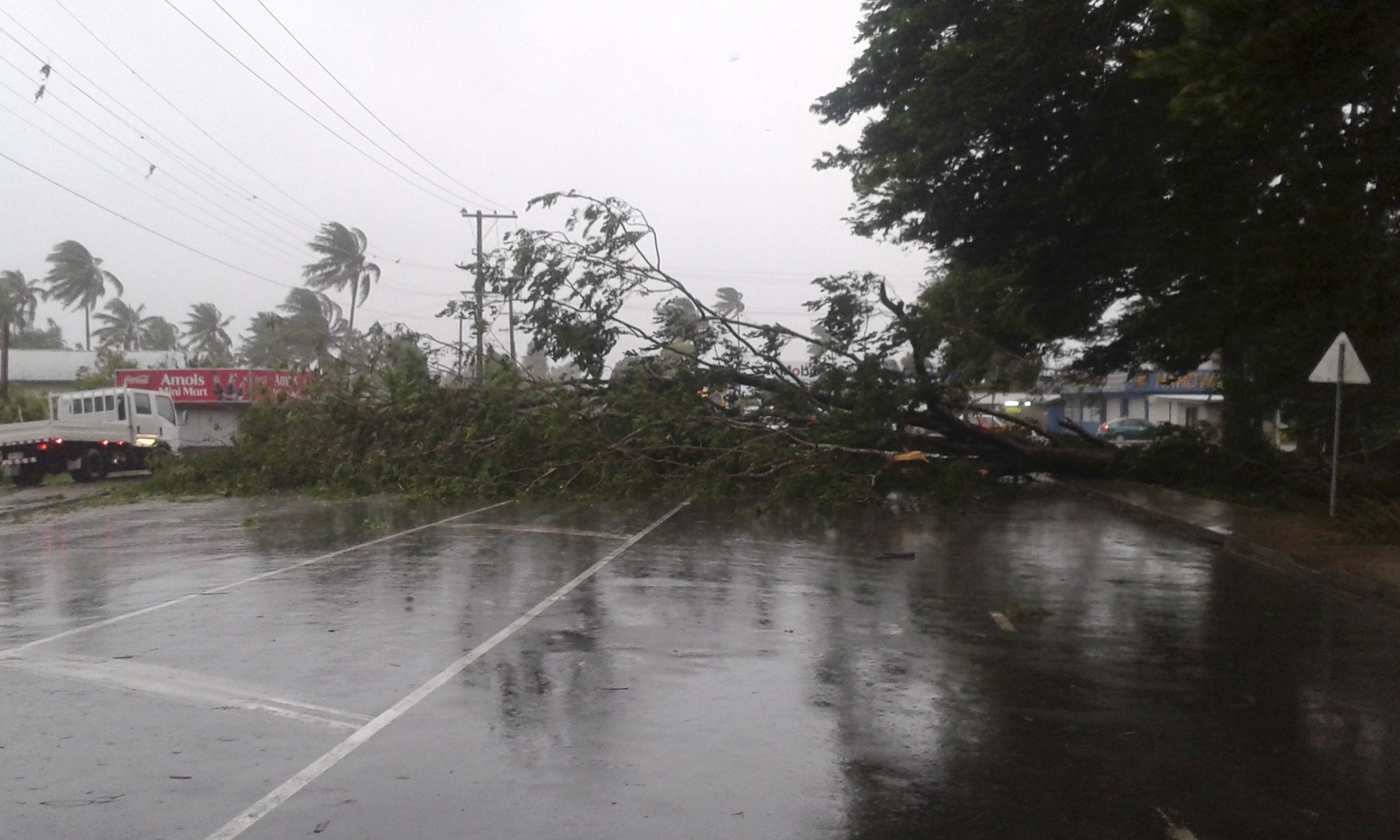 A tree blocks a road after it was blown down by the encroaching cyclone Winston in Nakasi, Fiji, Saturday, Feb. 20, 2016. The Pacific island nation of Fiji is hunkering down as a formidable cyclone with winds of 300 kilometers (186 miles) per hour approaches.