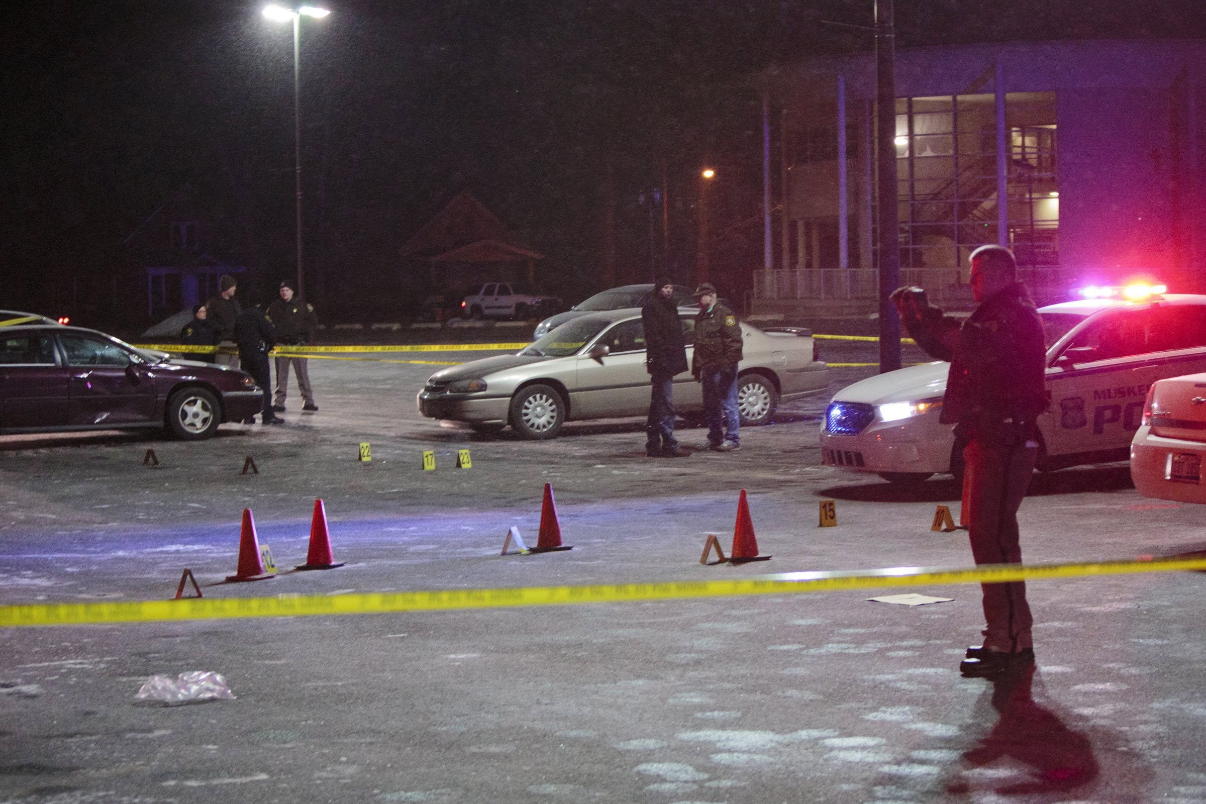 Officials investigate shooting scenes in the parking lot of Muskegon Heights High School in Muskegon Heights, Mich., Tuesday. The shootings happened around 9:30 p.m. after a basketball game at the high school.