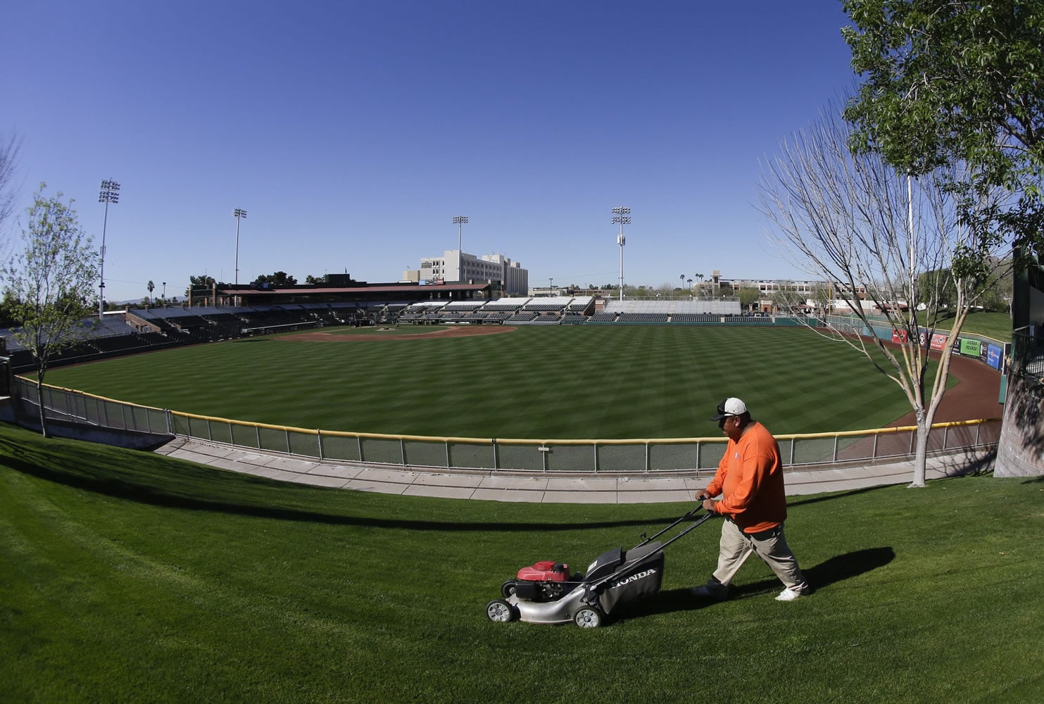 A member of the grounds crew cuts the grass Wednesday in the outfield where the San Francisco Giants are set to begin their spring baseball season in Scottsdale, Ariz. High temperatures in nearby Phoenix broke a record.