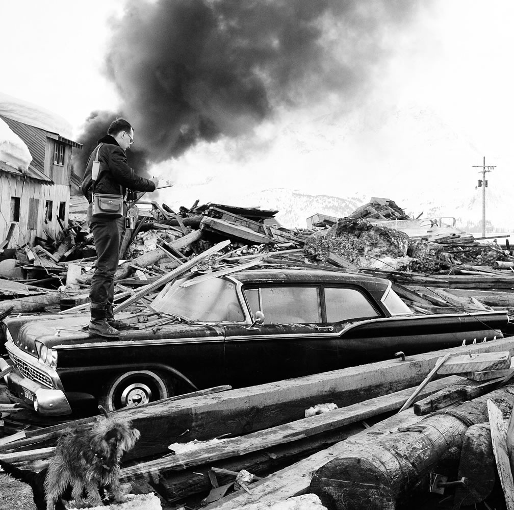 A photographer surveys the wreckage in March 1964 as smoke rises from burning oil storage tanks at Valdez, Alaska. On Monday, scientists say they&#039;ve pinpointed the cause of tsunami waves that followed the 1964 Great Alaska Earthquake.