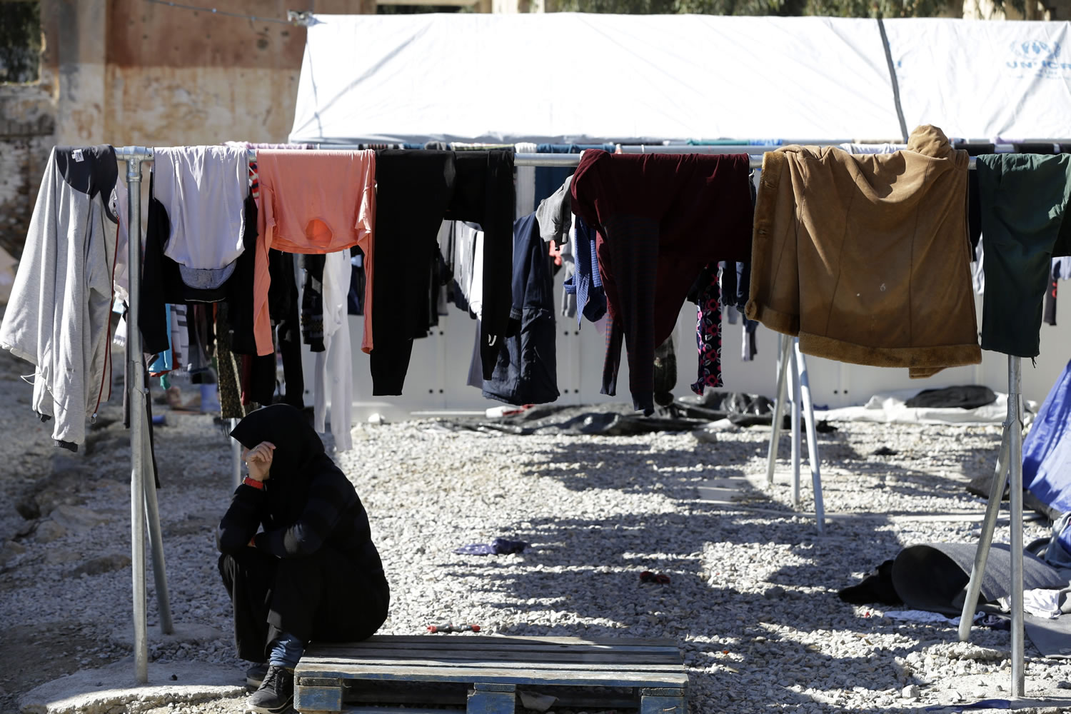 A girl sits under laundry at a refugee camp at Lakki port on the southeastern Greek island of Leros, Tuesday.