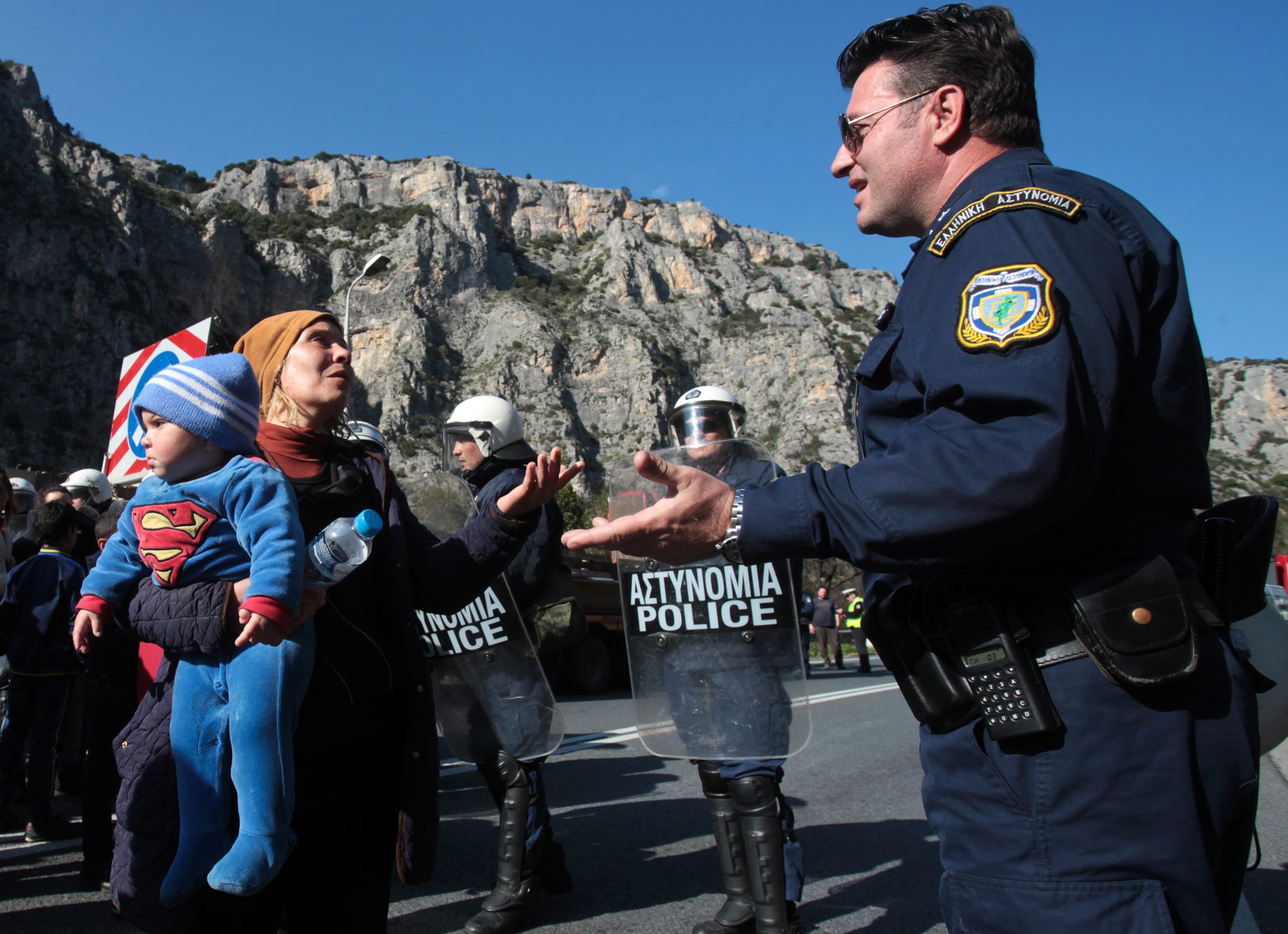 A police officer argues with migrants during a protest Thursday on a highway near Larissa, Greece. Tougher Balkan border controls have left thousands of people stranded in Greece, where some 4,000 migrants and refugees continue to arrive daily.