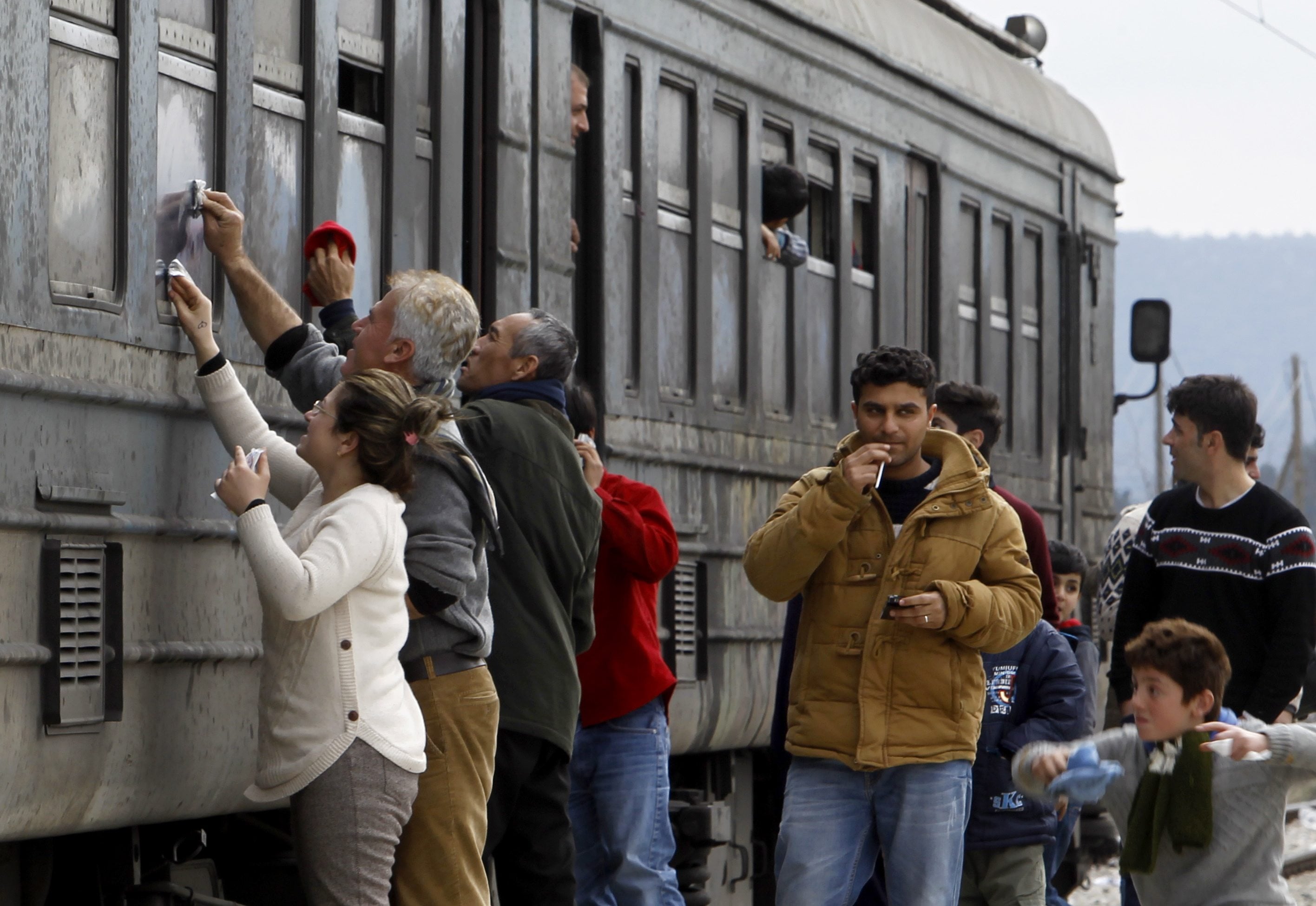 Refugees clean windows of a train before departing towards Serbia, at the transit center for refugees, near the southern Macedonia&#039;s town of Gevgelija, Monday. European Union nations anxious to stem the flow of asylum-seekers coming through the Balkans are increasingly considering sending more help to non-member Macedonia as a better way to protect European borders instead of relying on EU member Greece. Macedonia started reinforcing the border fence with Greece, doubling it with another fence, which is expected to increase the control of the migrant flow.