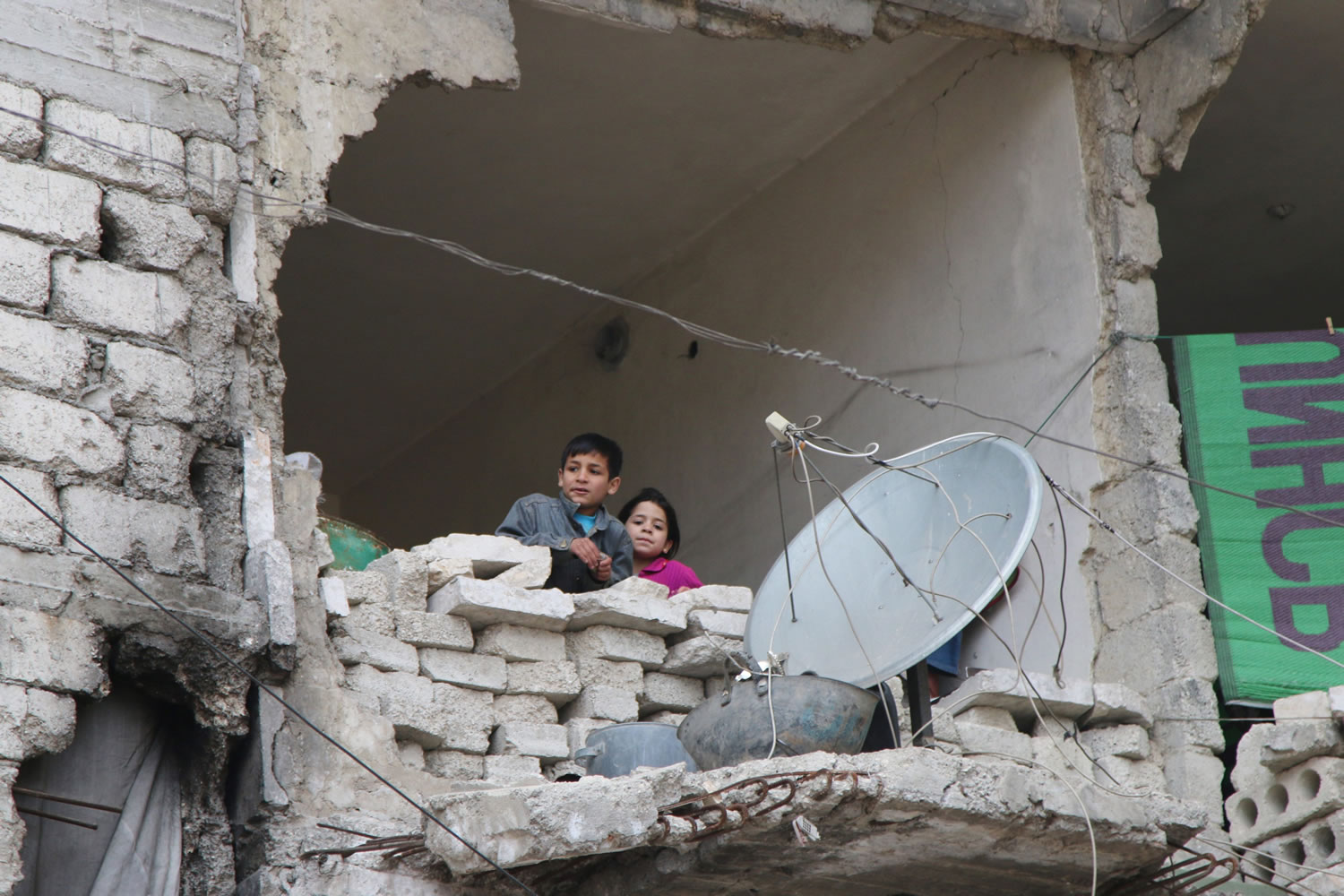 Children peer from a partially destroyed home Thursday in Aleppo, Syria.
