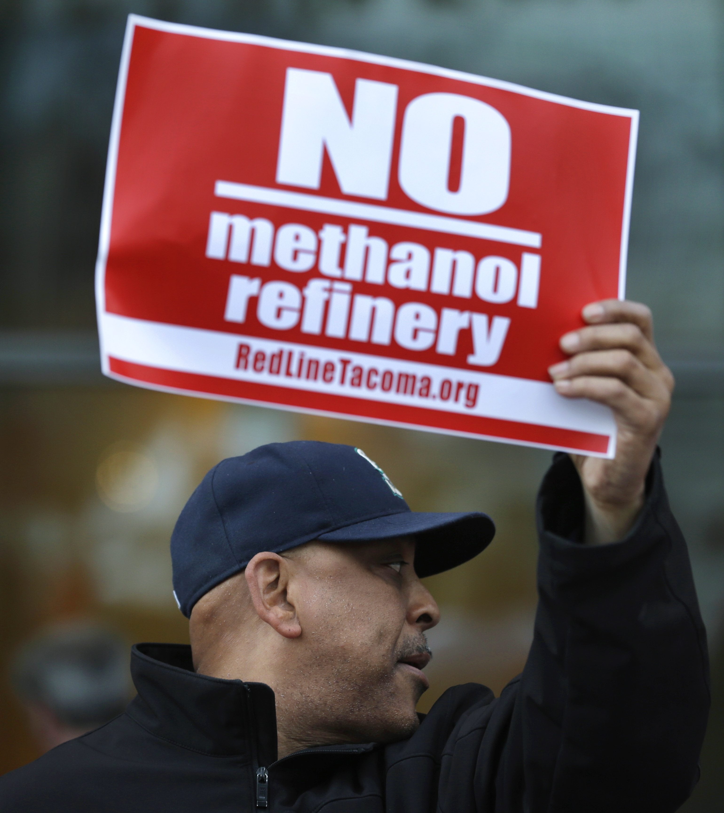 Seth Hill of Tacoma holds a sign as he protests Feb. 10 in Tacoma outside a public meeting to gather opinion on a proposed methanol plant that would be built at the Port of Tacoma. (Ted S.