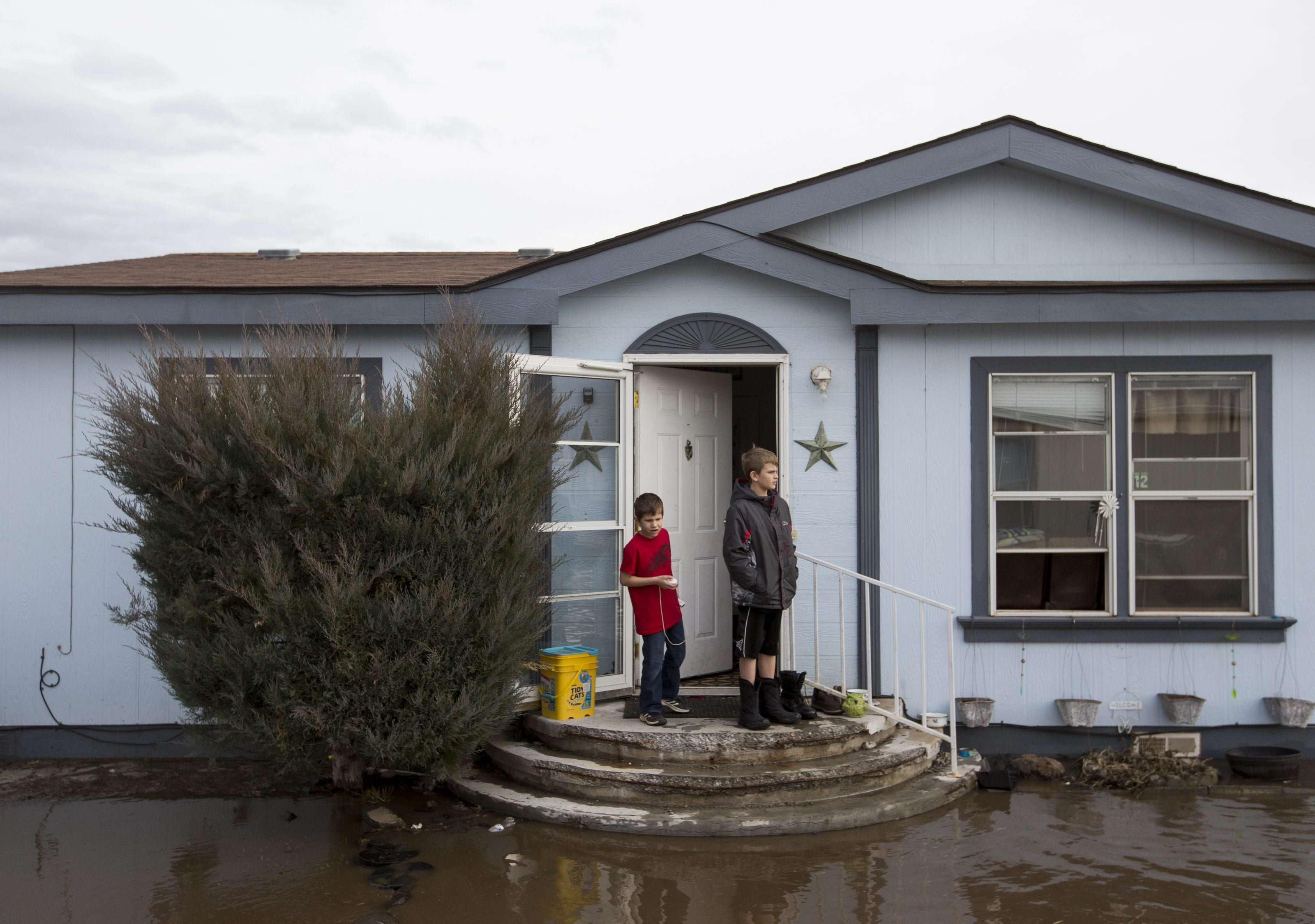 In this Monday, Feb. 15, 2016, photo, Cousins Jordan Ward, left, and Chris Sanborn, right, look at flood water in front of Ward's home in the Riverview Manor neighborhood of Yakima, Wash. A President's Day storm brought record rainfall to the Pacific Northwest and sent rivers overflowing their banks in Western Washington on Tuesday.