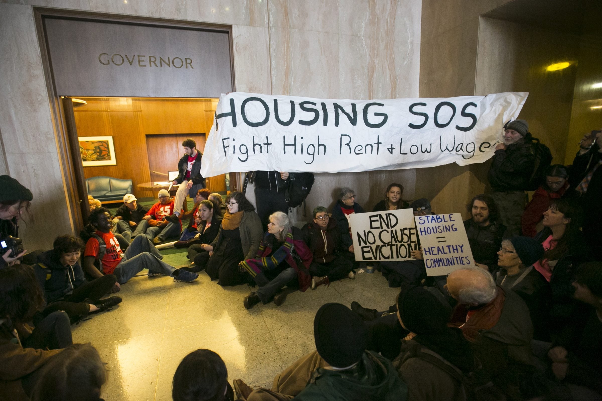 Demonstrators call for a fight against high rents and low wages as they stage a sit-in Thursday at the doorway of the governor&#039;s office at the Capitol in Salem, Ore. The protesters began their chants minutes after the House began hearing a bill to increase the minimum wage. (Molly J.