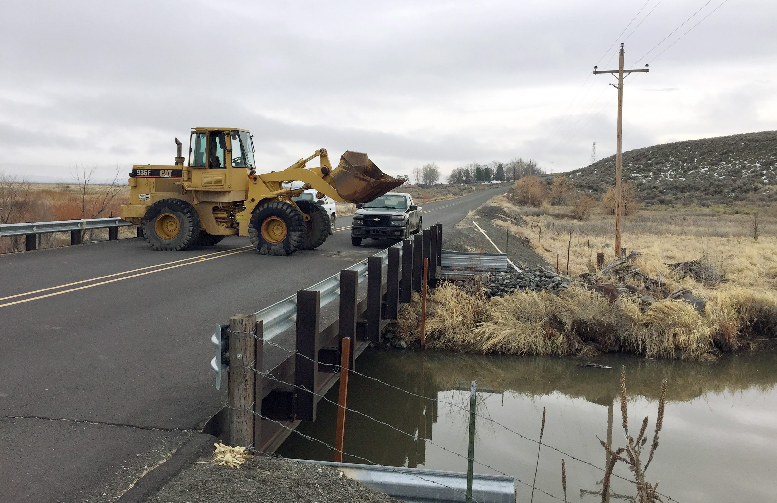 Trucks and a front-end loader block the road to the Malheur Wildlife Refuge at the site of an FBI checkpoint outside of Burns, Ore., on Friday. The FBI allowed a group of reporters to move nearer to the refuge Friday morning as part of a guided tour.
