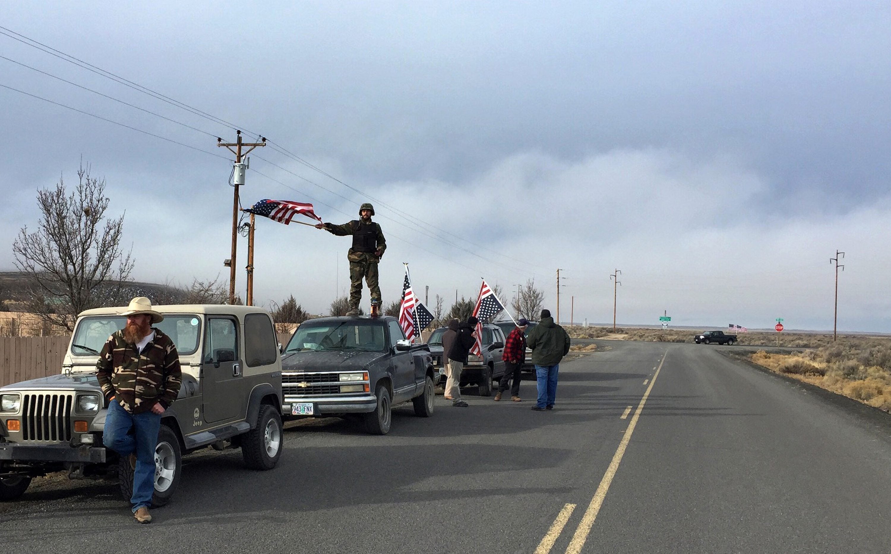 People wave American flags near the Malheur National Wildlife Refuge on Thursday near Burns, Ore. The last four armed occupiers of the national wildlife refuge in eastern Oregon said they would turn themselves in Thursday morning, after law officers surrounded them in a tense standoff.