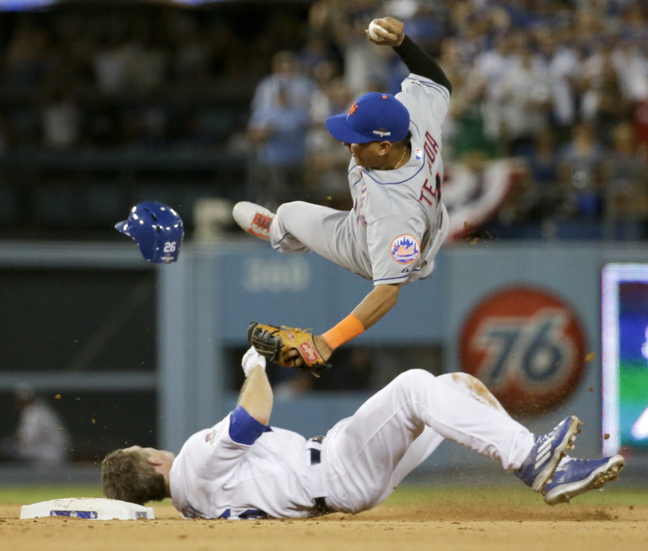 New York Mets shortstop Ruben Tejada, goes over the top of Los Angeles Dodgers' Chase Utley who broke up a double play during the seventh inning in Game 2 of baseball's National League Division Series, in Los Angeles on Oct. 10, 2015. Major League Baseball and the players' association have banned rolling block slides to break up potential double plays, hoping to prevent a repeat of the takeout by Dodgers' Chase Utley that broke a leg of Mets Ruben Tejada in last years playoffs. Under the rules change announced Thursday, Feb. 25, 2016, a runner must make a "bona fide slide," defined as making contact with the ground ahead of the base, being in position to reach the base with a hand or foot and to remain on it, and sliding within reach of the base without changing his path to initiate contact with a fielder.