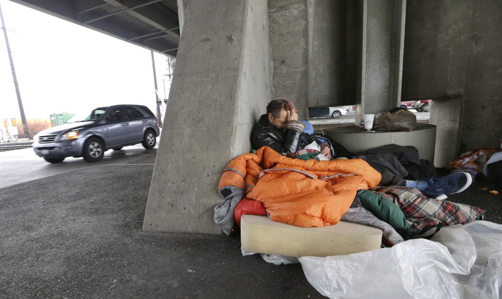Aaron Benedict Morman wakes up in a nest of sleeping bags and a foam pad beneath a viaduct as traffic passes near him in Seattle. Morman said that he&#039;s been homeless for over 30 years, the last two in Seattle on Feb. 9.