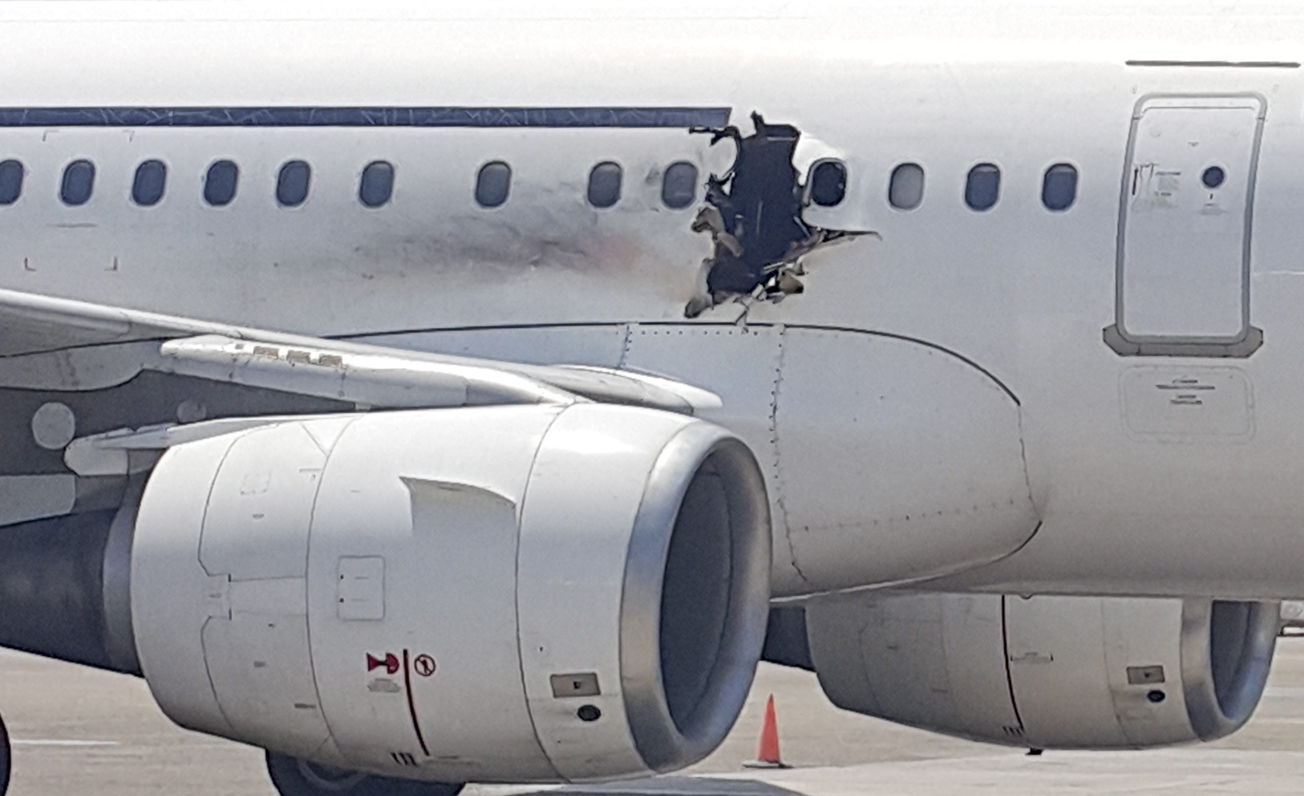 A hole is photographed in a plane operated by Daallo Airlines as it sits on the runway of the airport in Mogadishu, Somalia. A gaping hole in the commercial airliner forced it to make an emergency landing at Mogadishu's international airport late Tuesday, officials and witnesses said.
