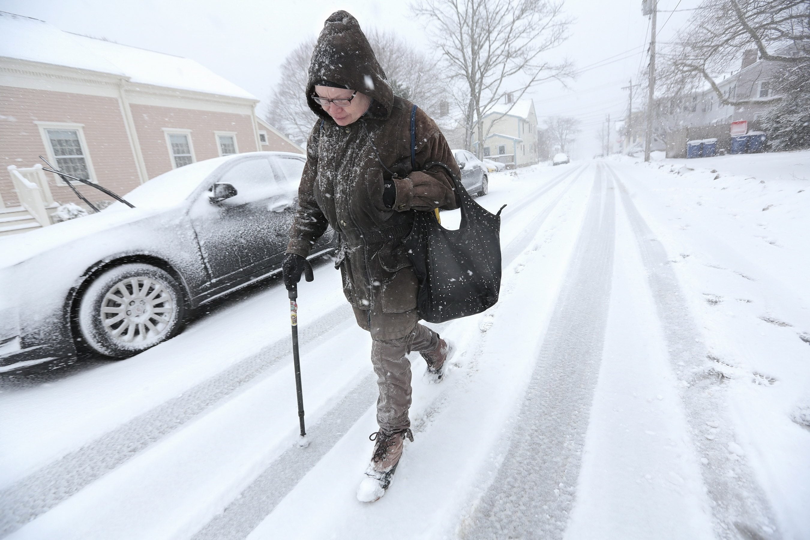 Anne Correia  walks in a snowstorm to visit her mother  at a nursing home on Monday in Fairhaven, Mass.   Coastal communities in Massachusetts are bracing for possible coastal flooding as a potent winter storm moves into the region.